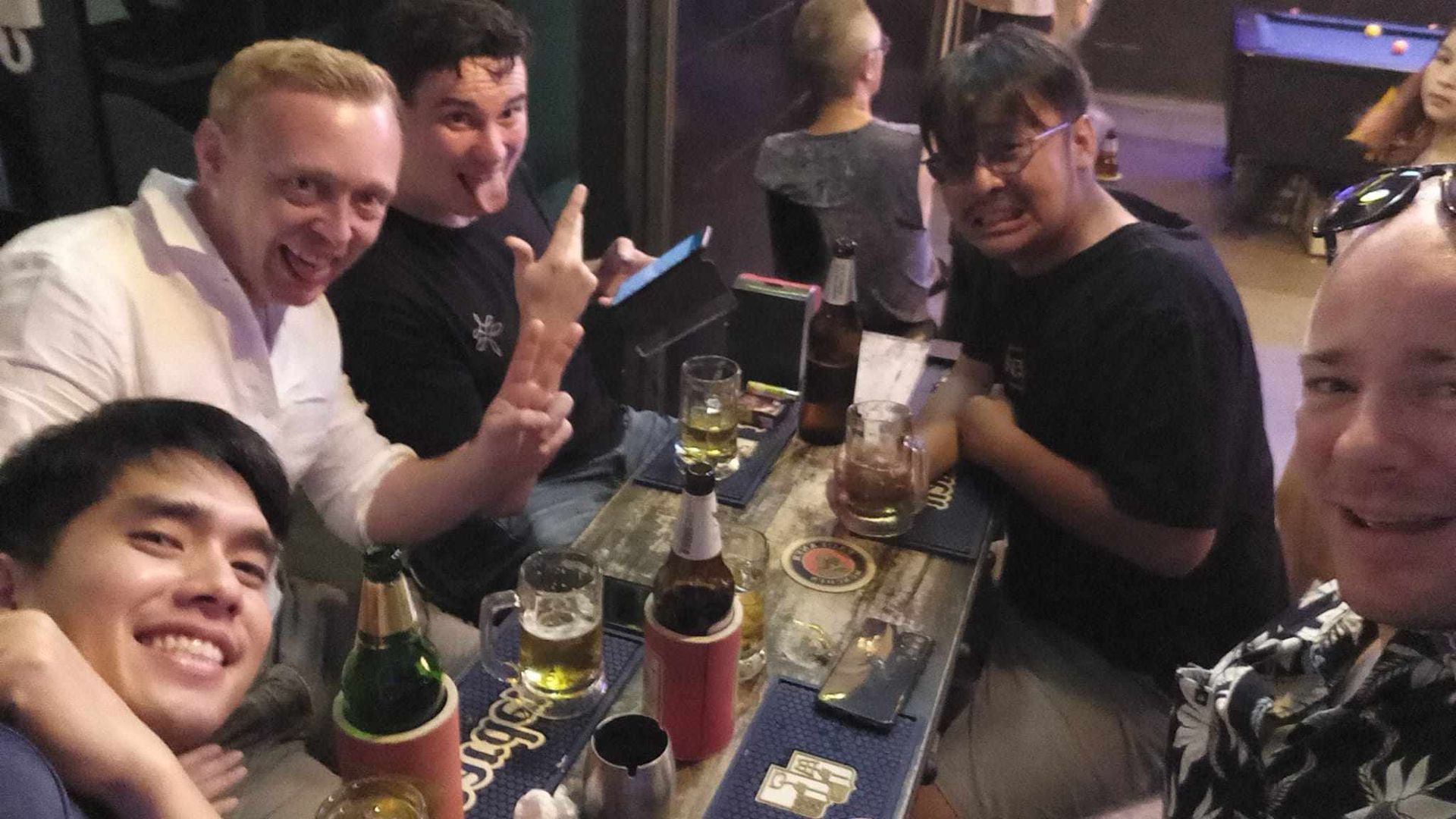 A group of men are sitting around a table with bottles of beer.