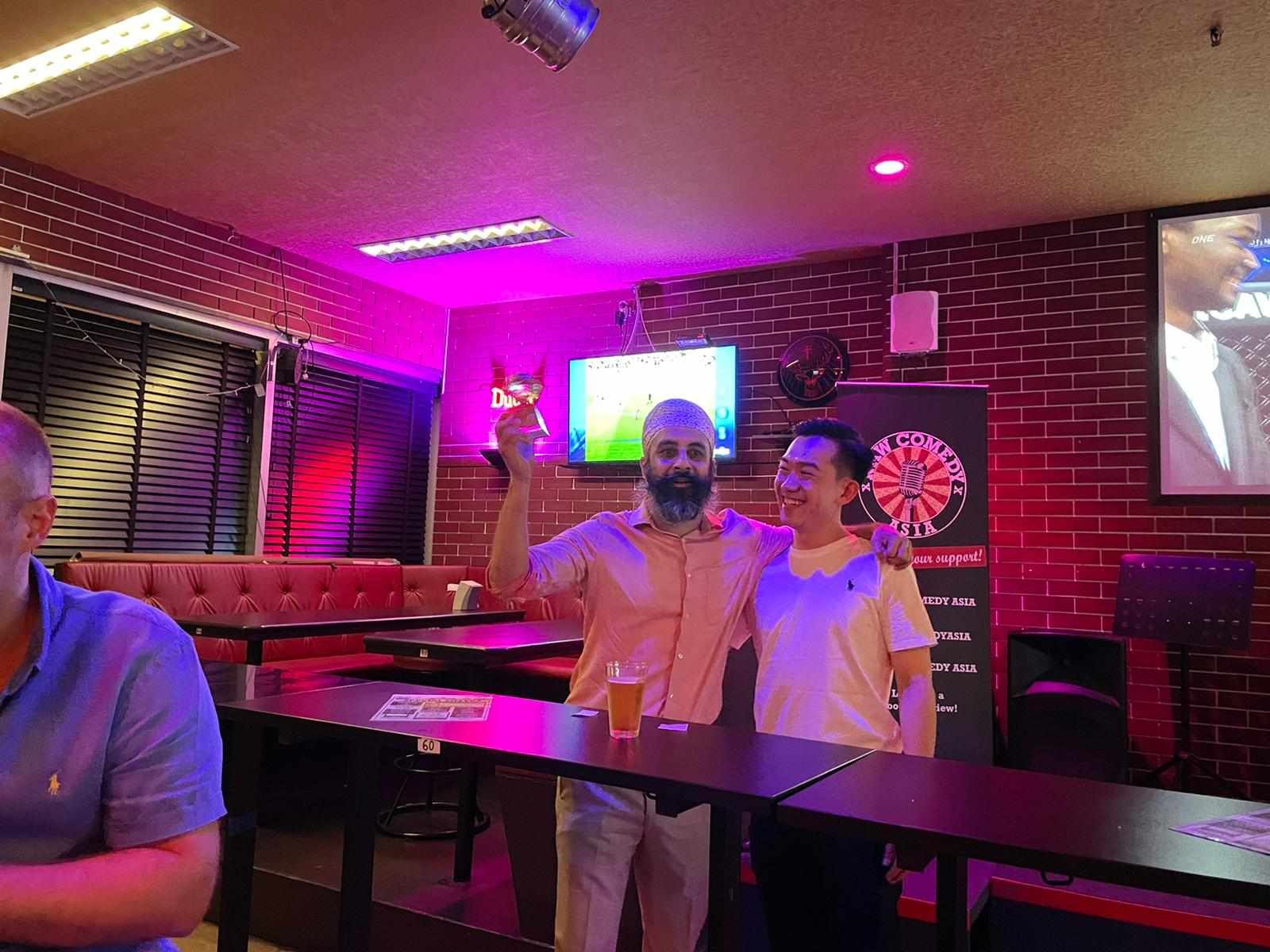 Two men are standing next to each other in a bar.