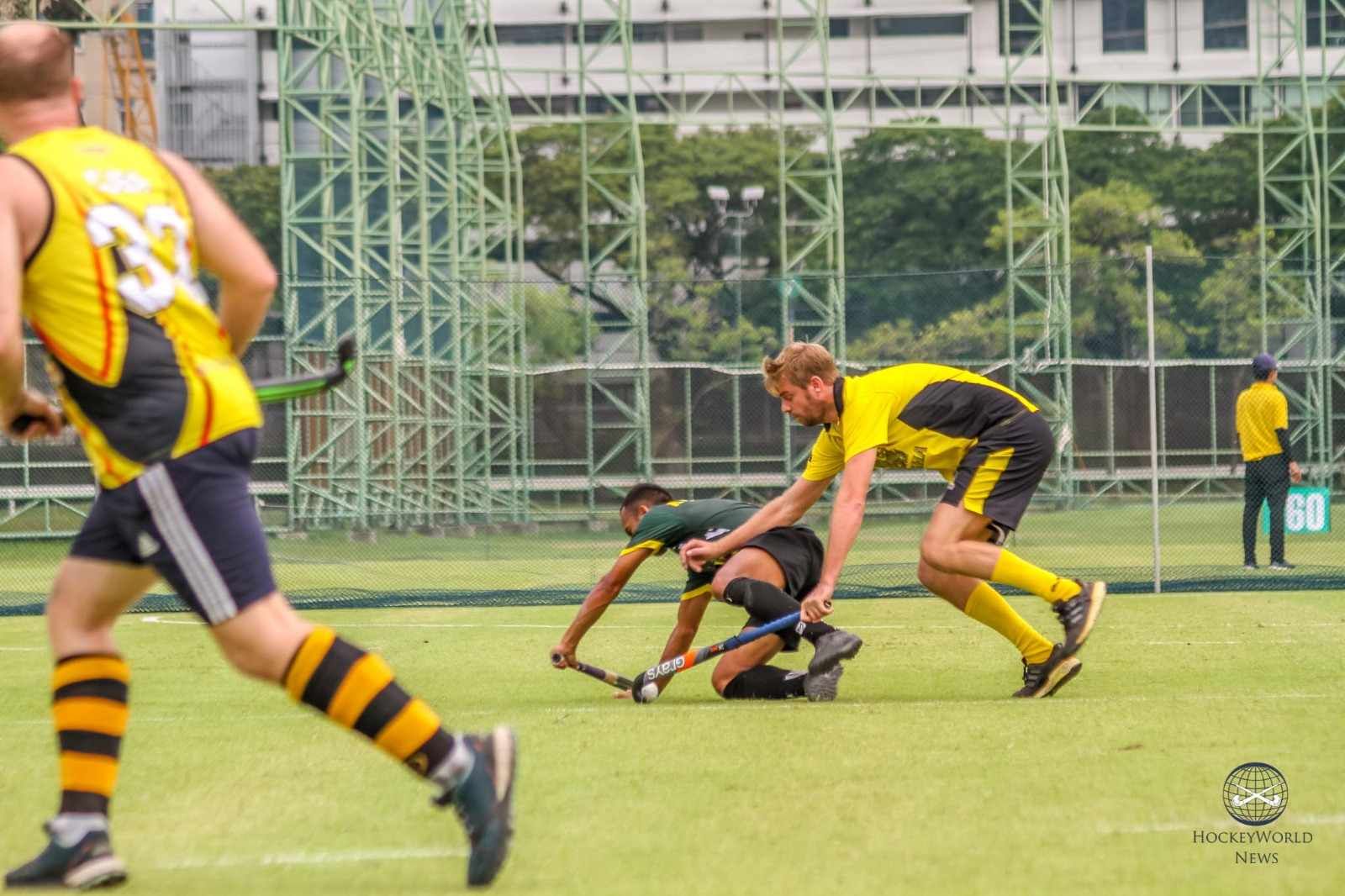A group of men are playing field hockey on a field.