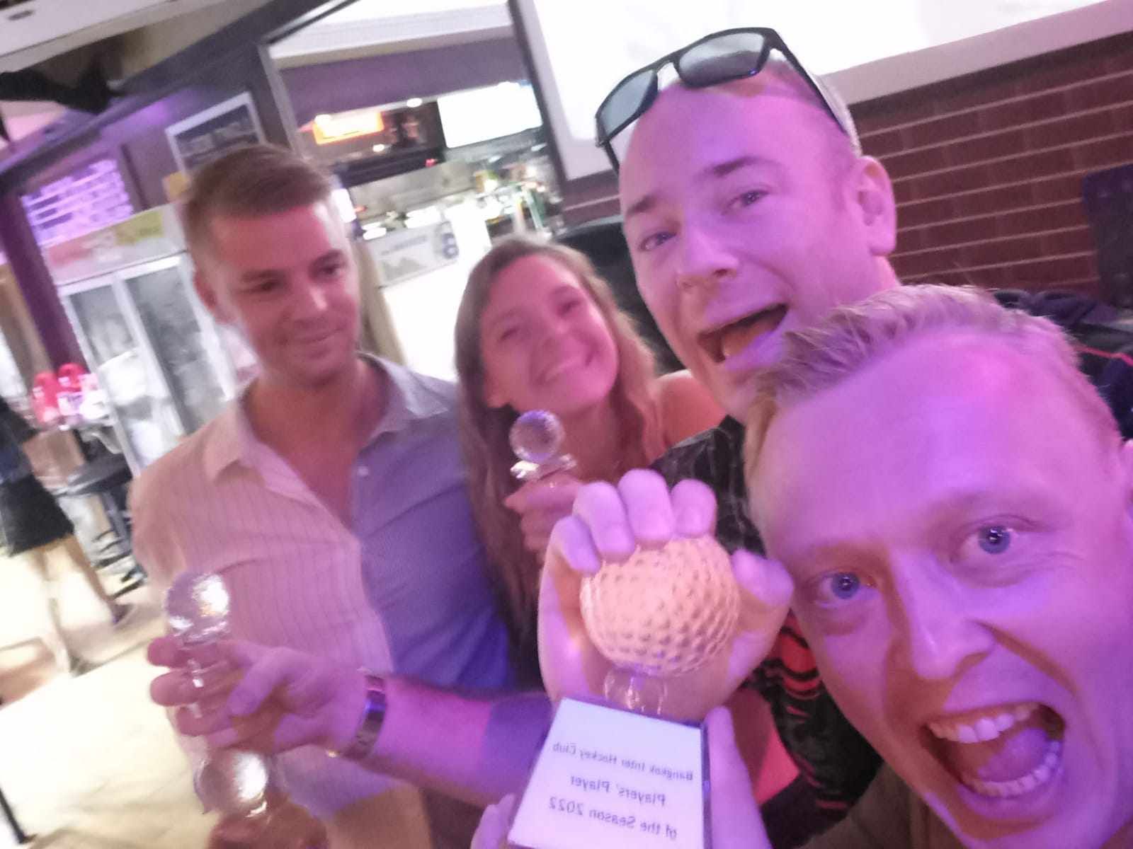 A group of people are posing for a picture and one of them is holding a golf ball.