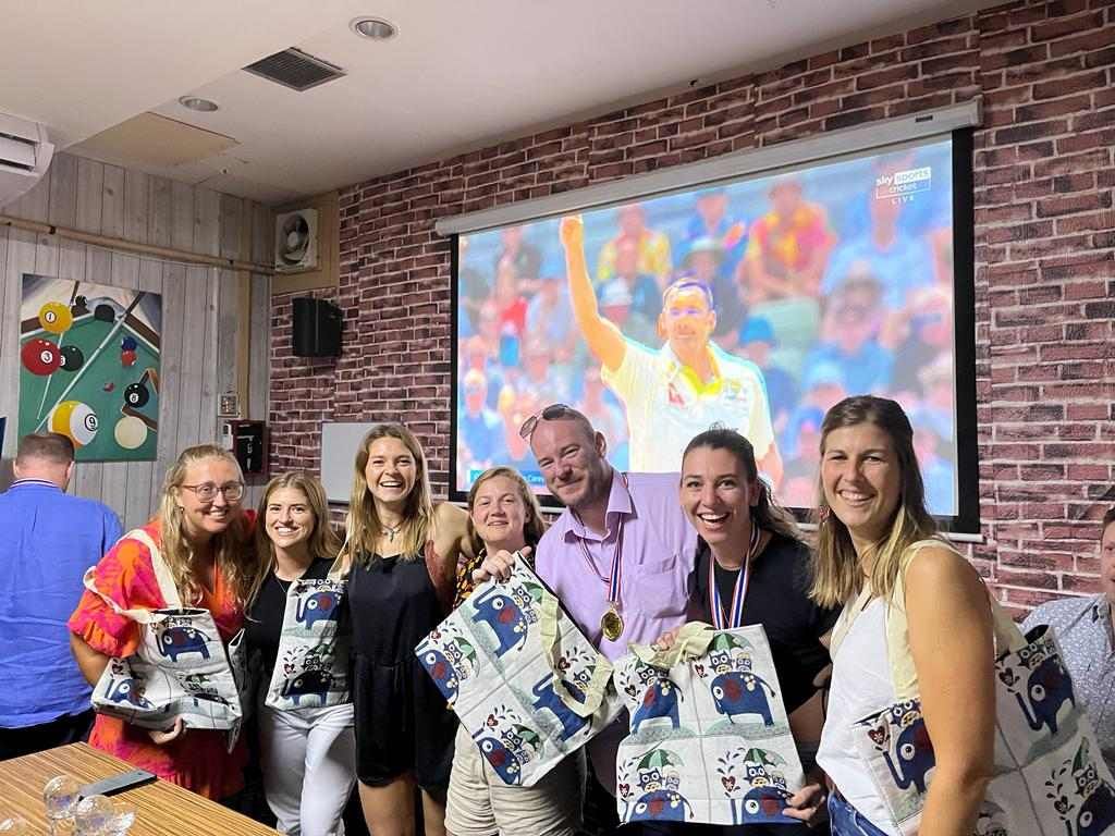 A group of people are posing for a picture in front of a large screen.