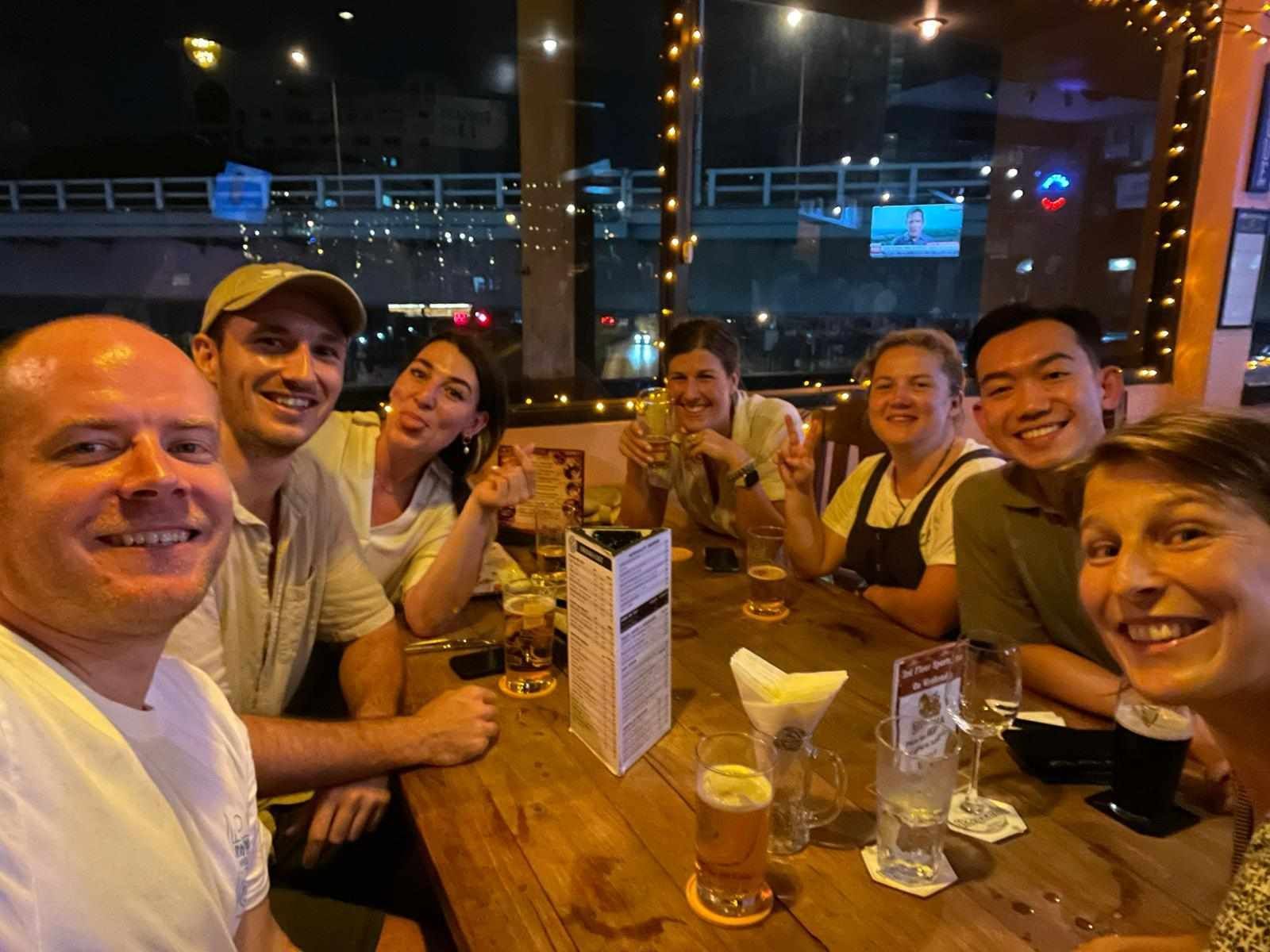 A group of people are sitting at a table drinking beer.