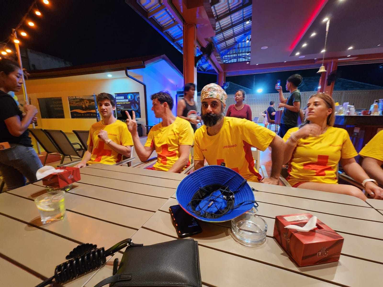 A group of people in yellow shirts are sitting at a table.