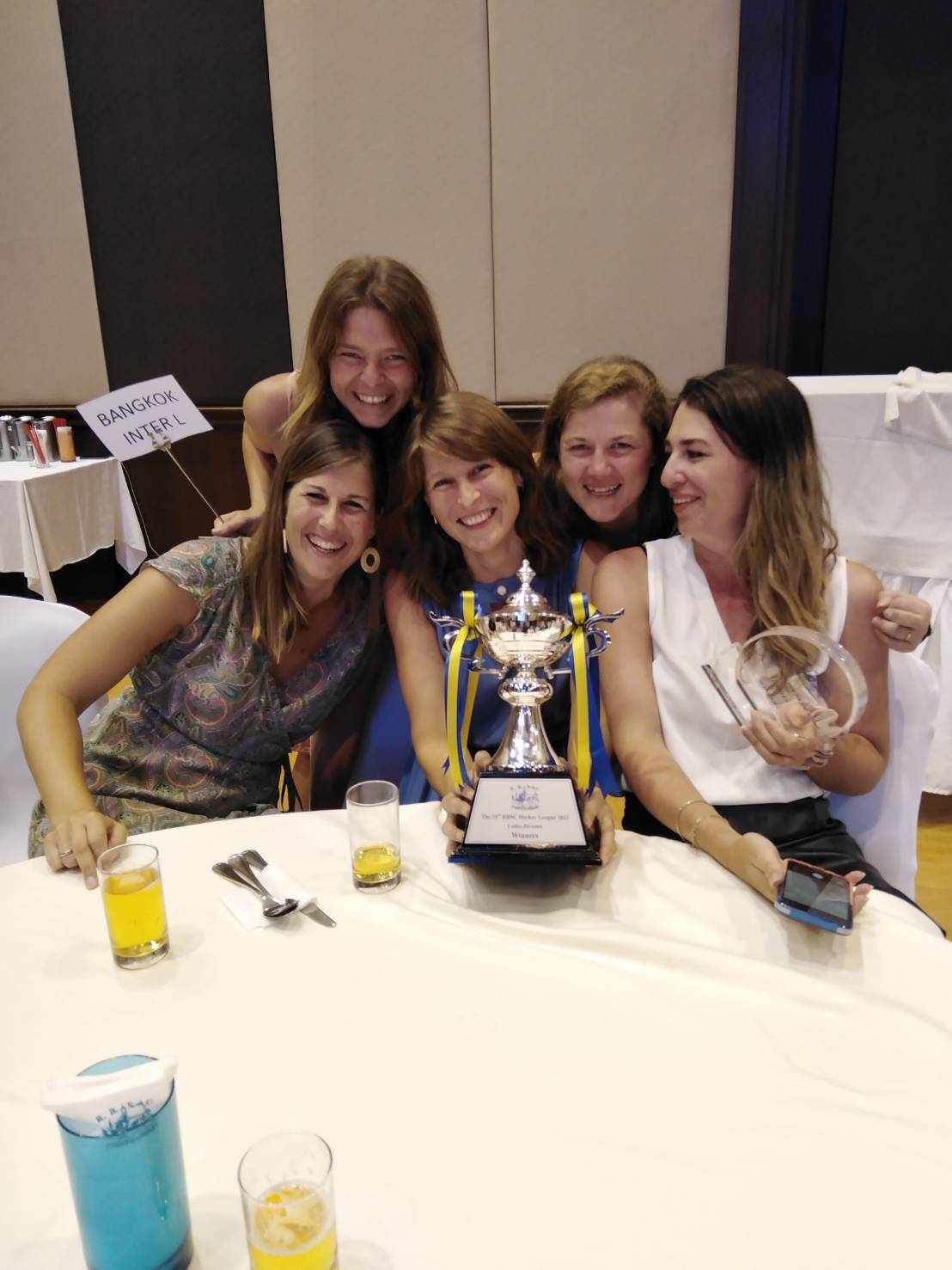 A group of women sitting around a table holding a trophy