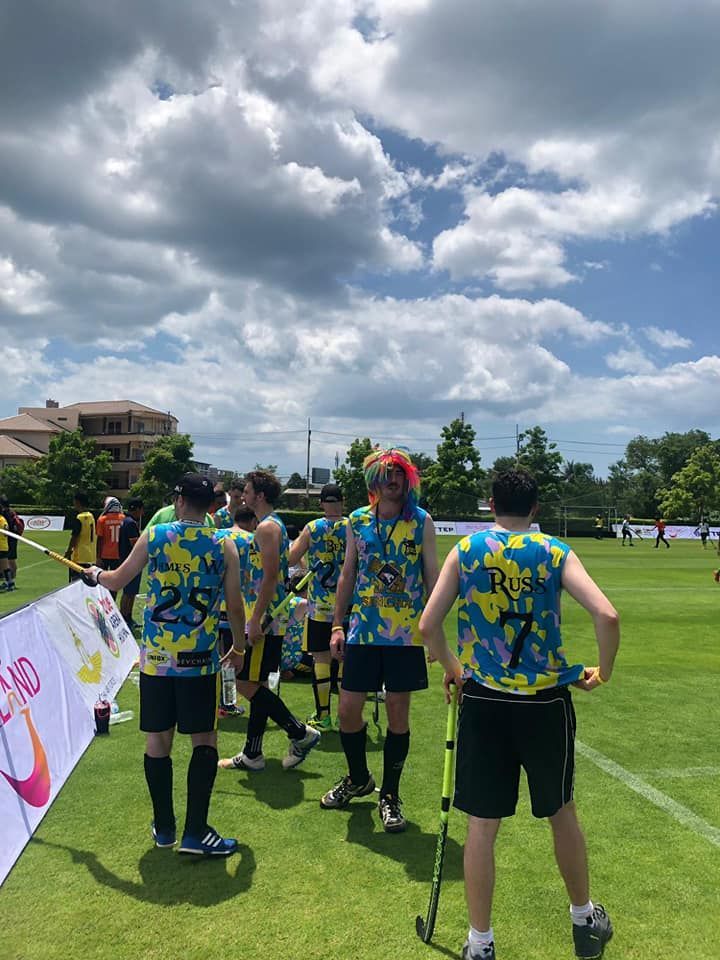 A group of people standing on top of a lush green field.