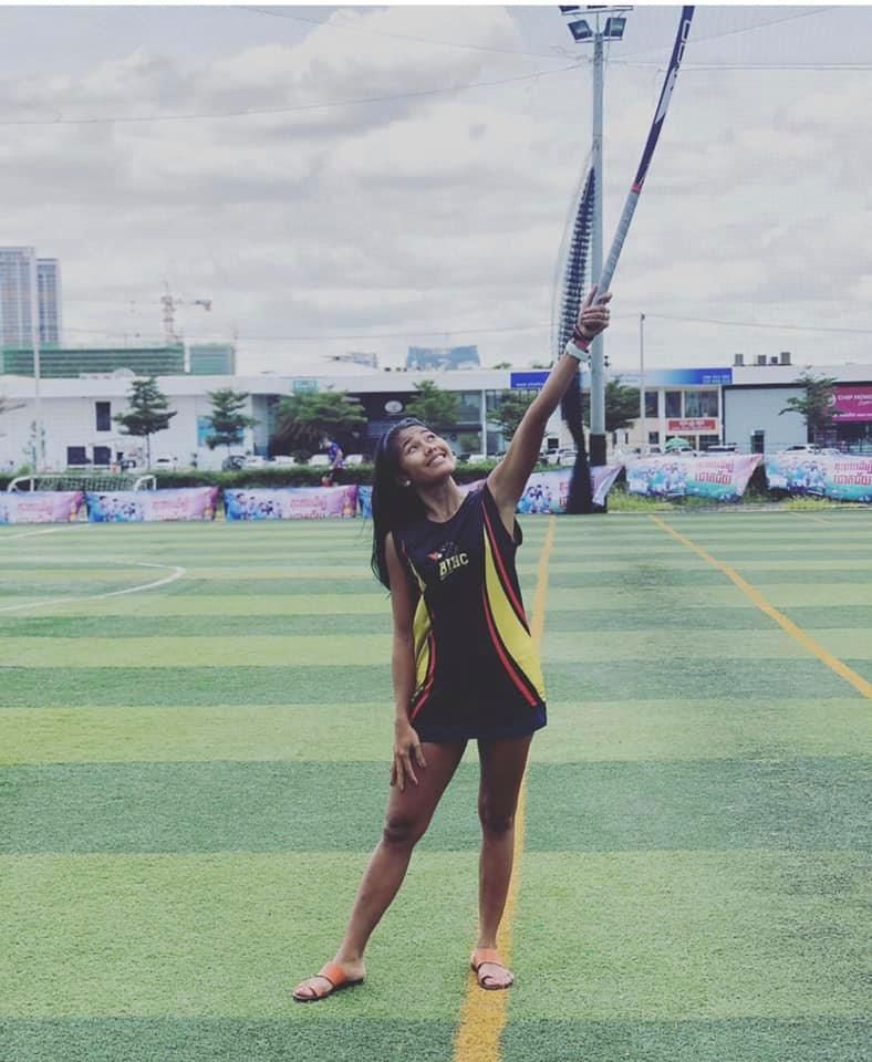 A girl is standing on a field holding a pole up in the air