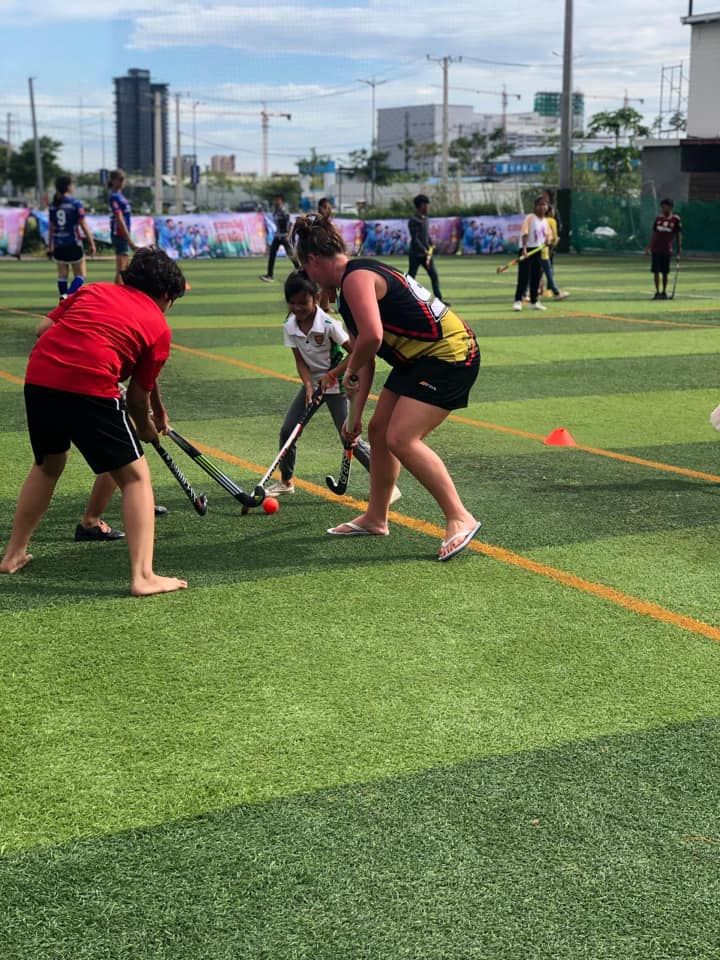 A group of people are playing field hockey on a field.