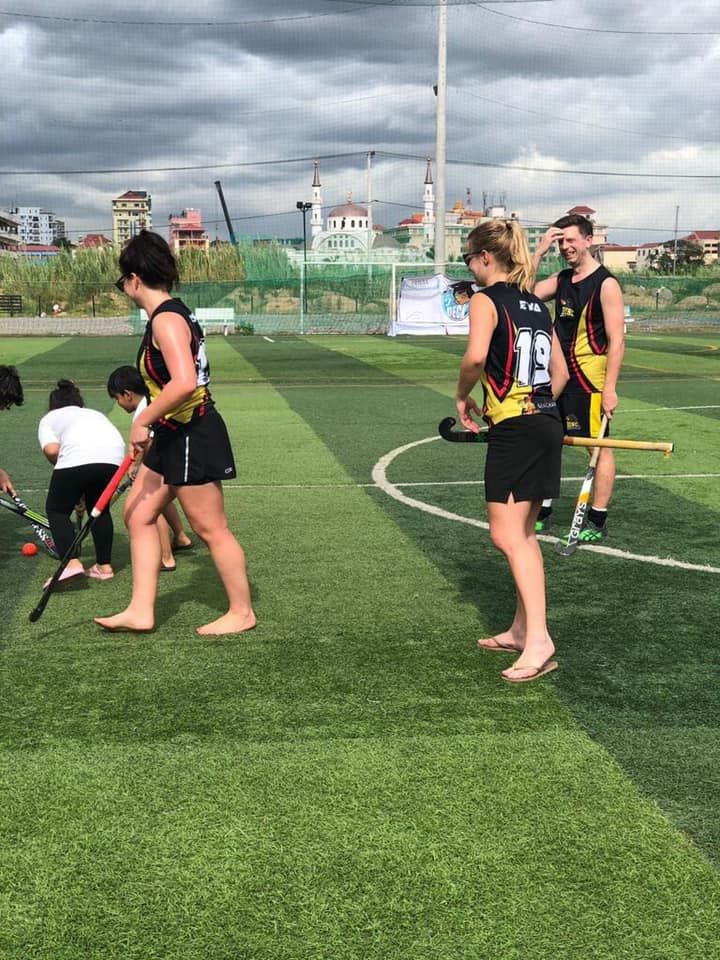 A group of people are playing field hockey on a field.