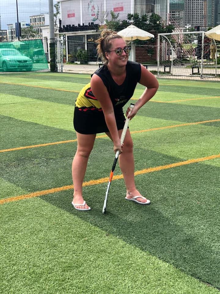 A woman is holding a hockey stick on a field.