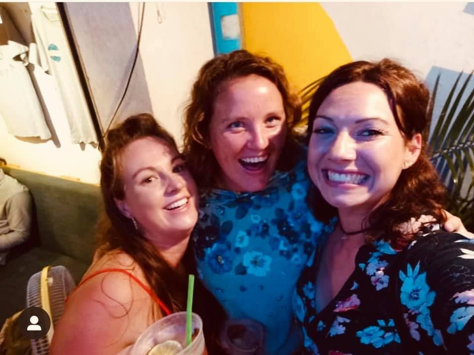 Three women are posing for a picture together and smiling