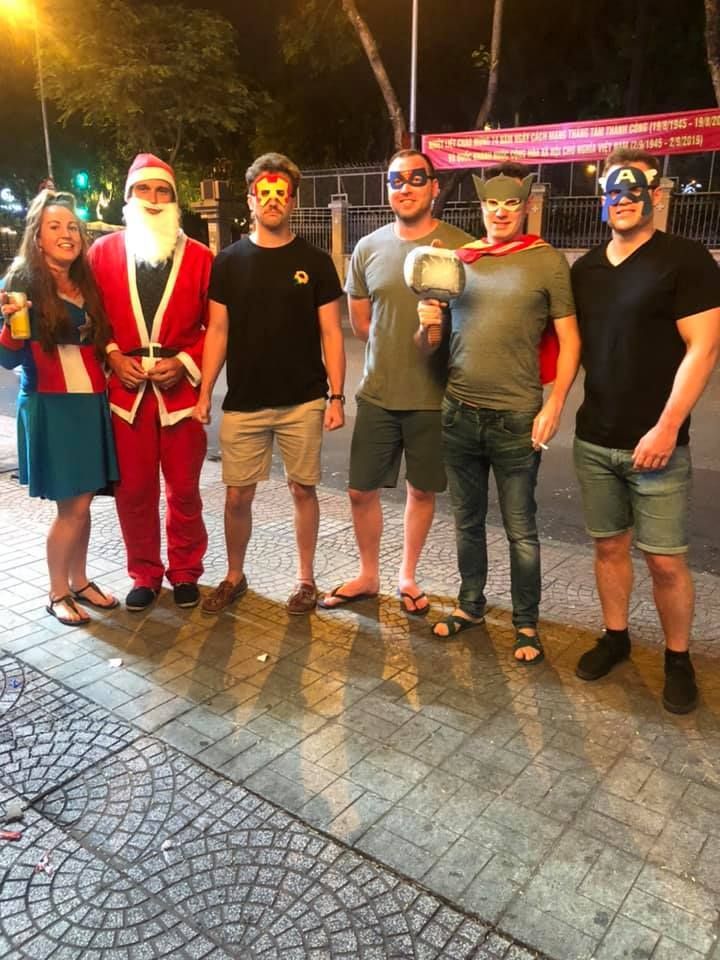 A group of people dressed in costumes are standing next to each other on a sidewalk.