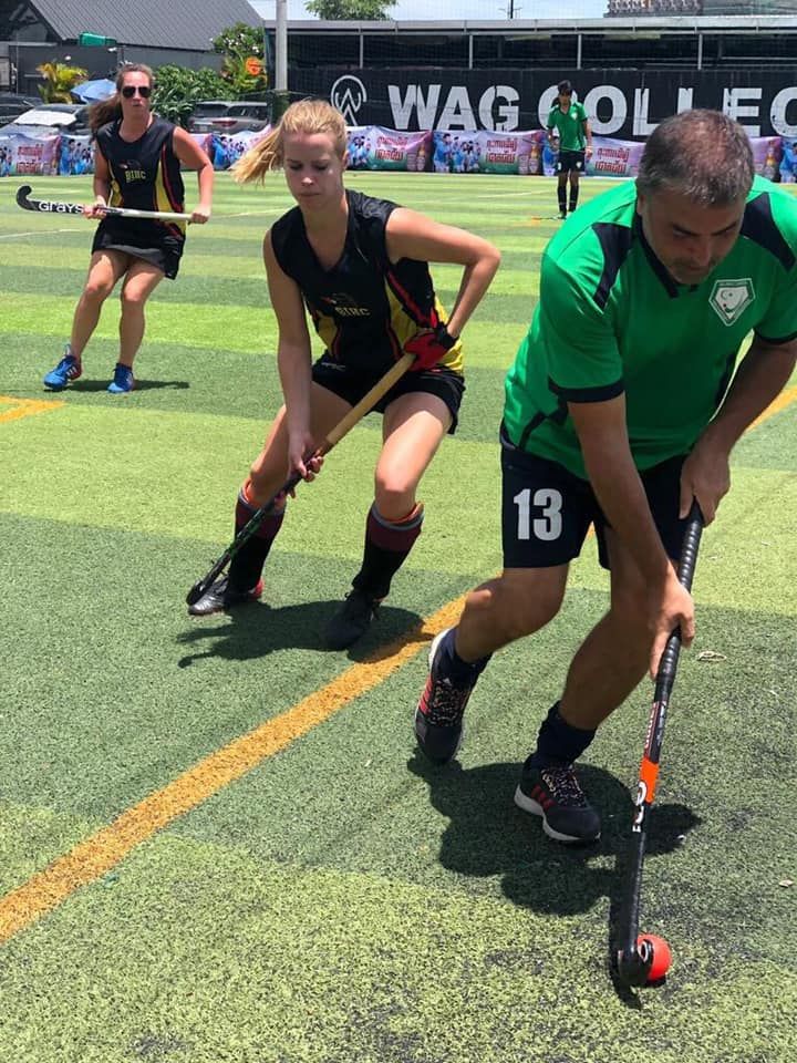 A group of people are playing field hockey on a field.