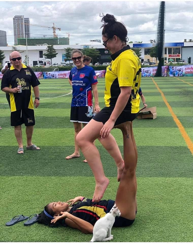 A woman is standing on a man 's feet on a soccer field.