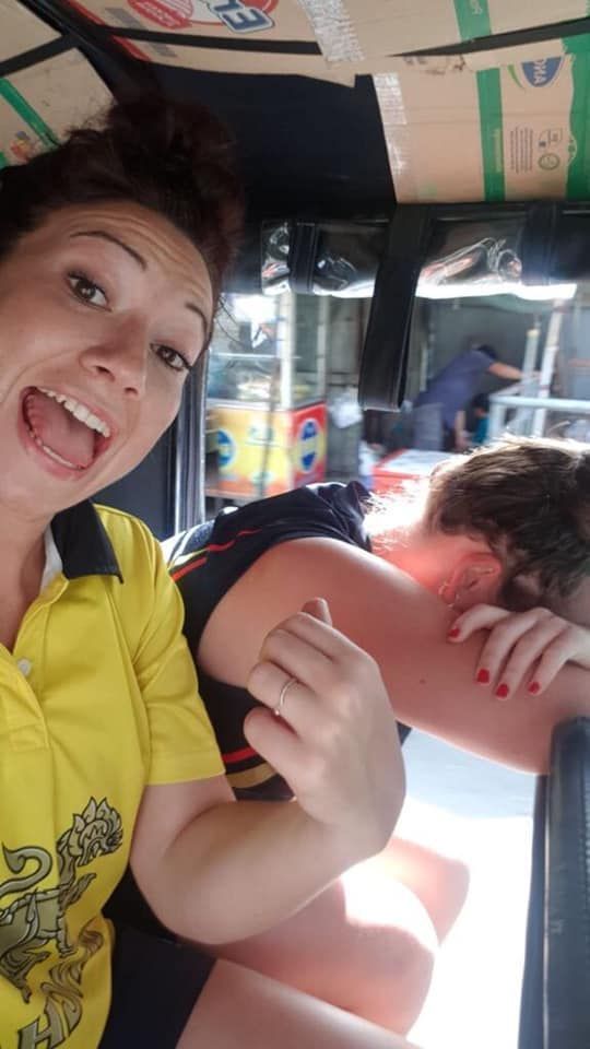 A woman is taking a selfie with another woman in a car.