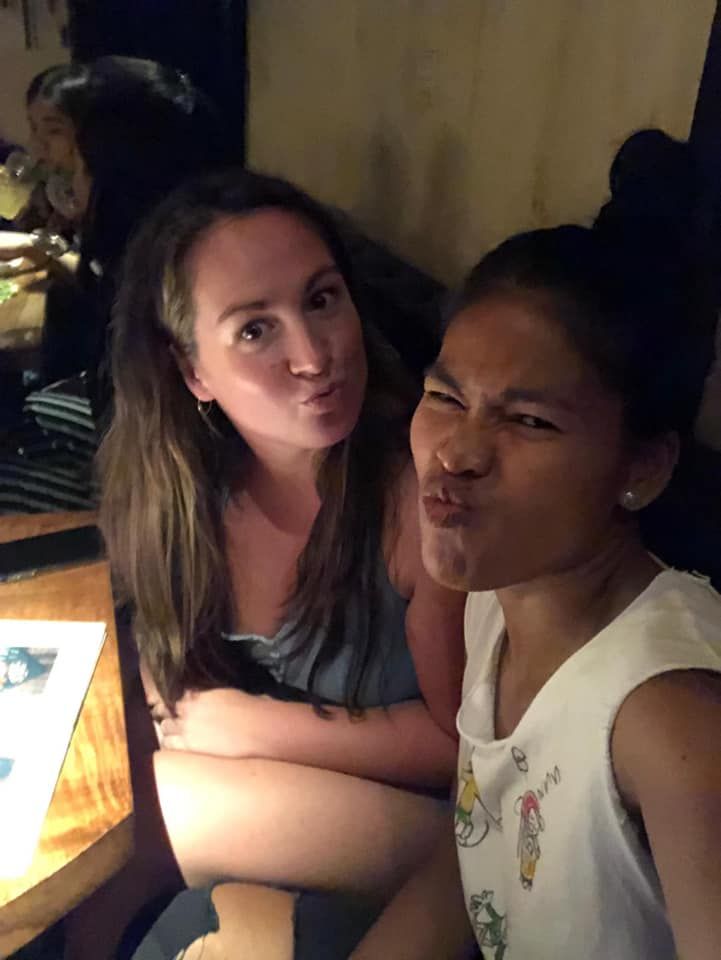 Two women are sitting at a table making funny faces.