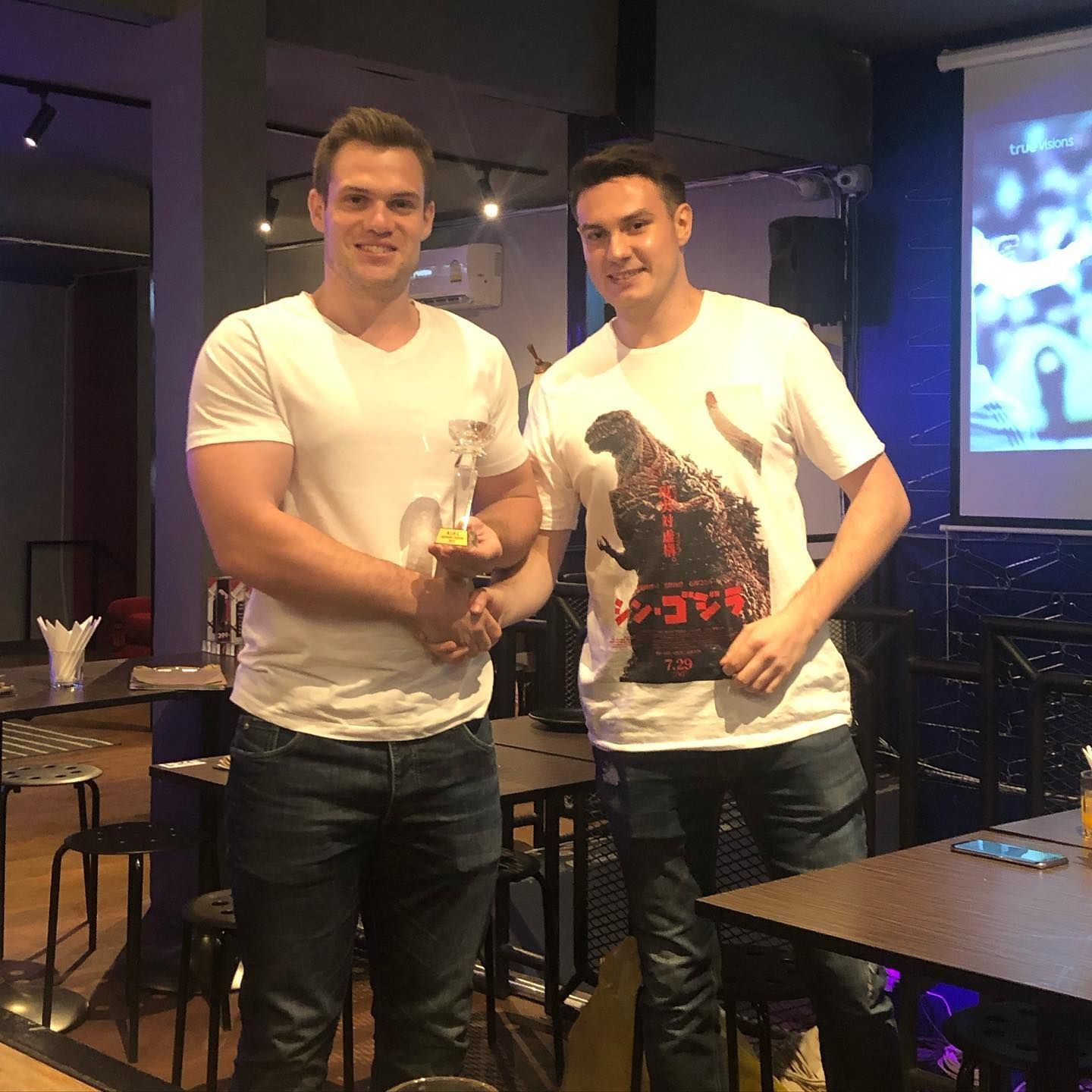 Two men are standing next to each other in a restaurant.