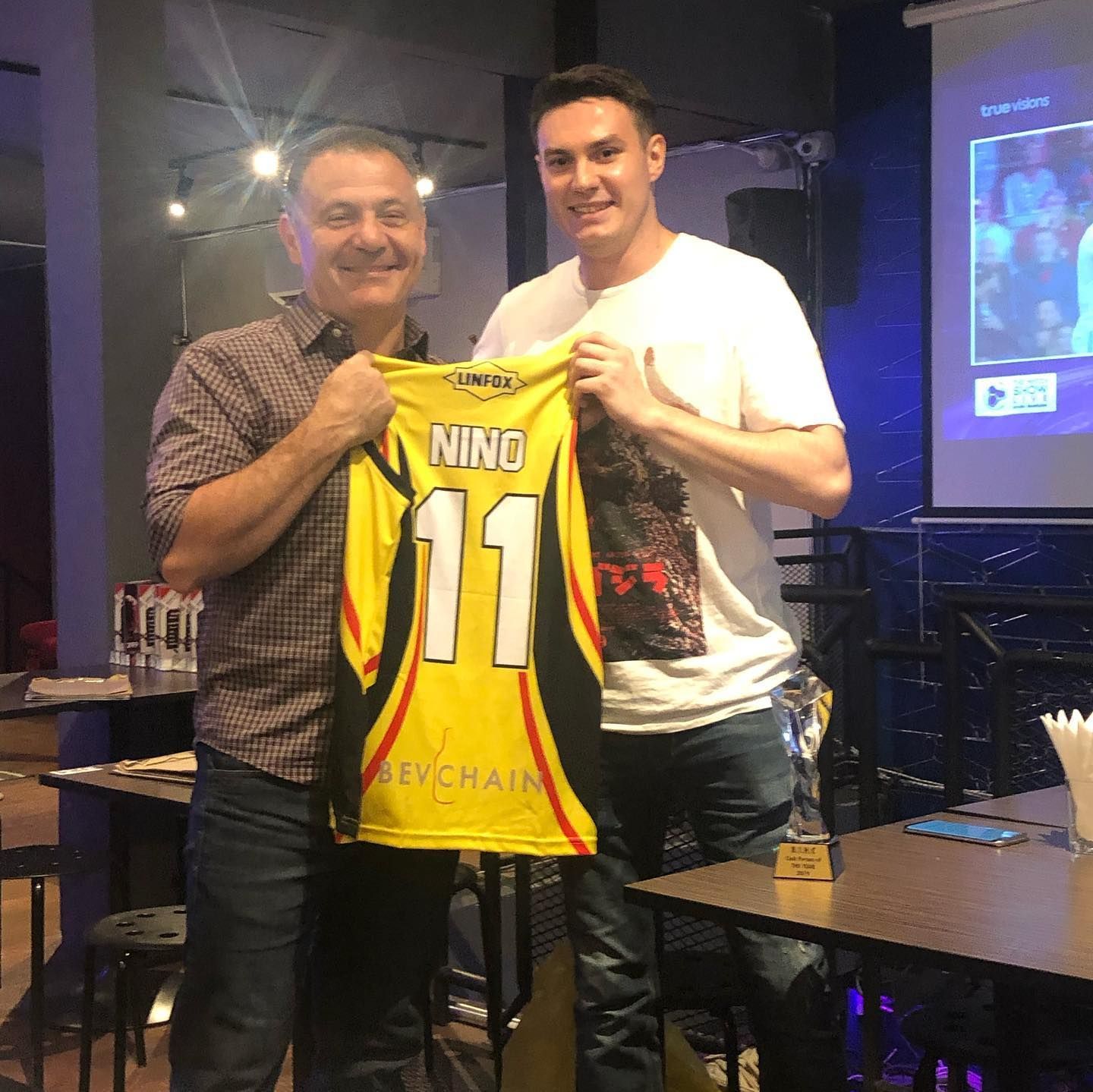 A man holding a jersey with the number 11 on it