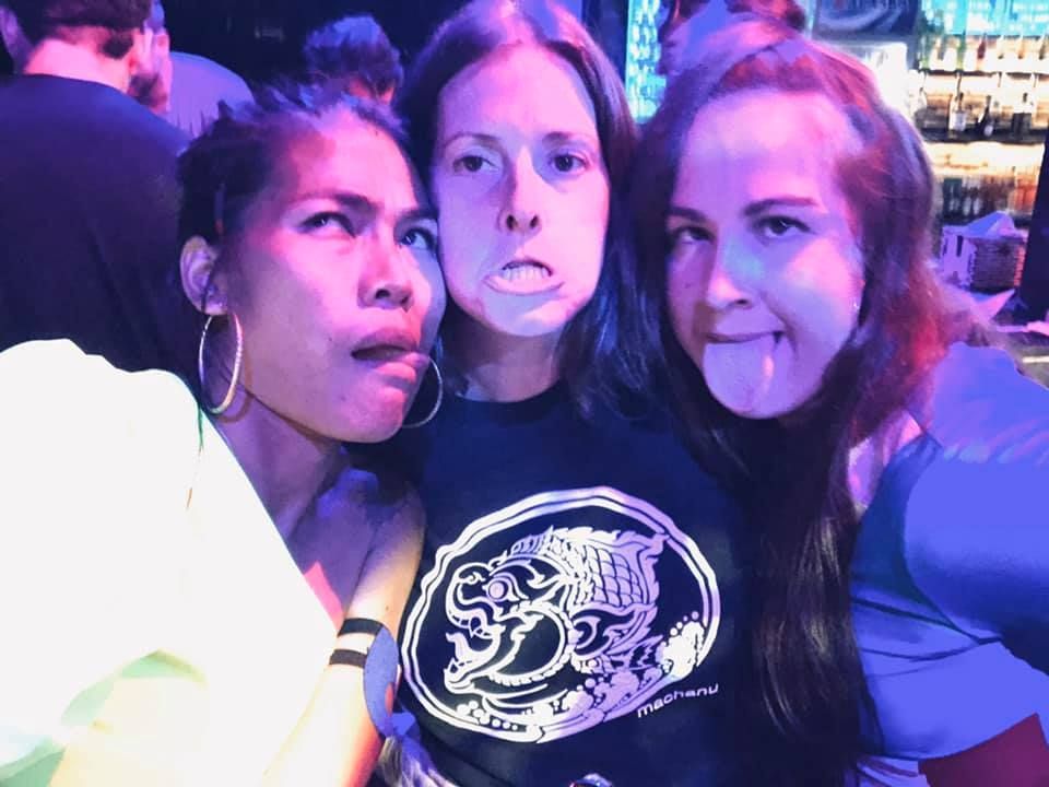 Three women posing for a picture with one wearing a shirt that says sd