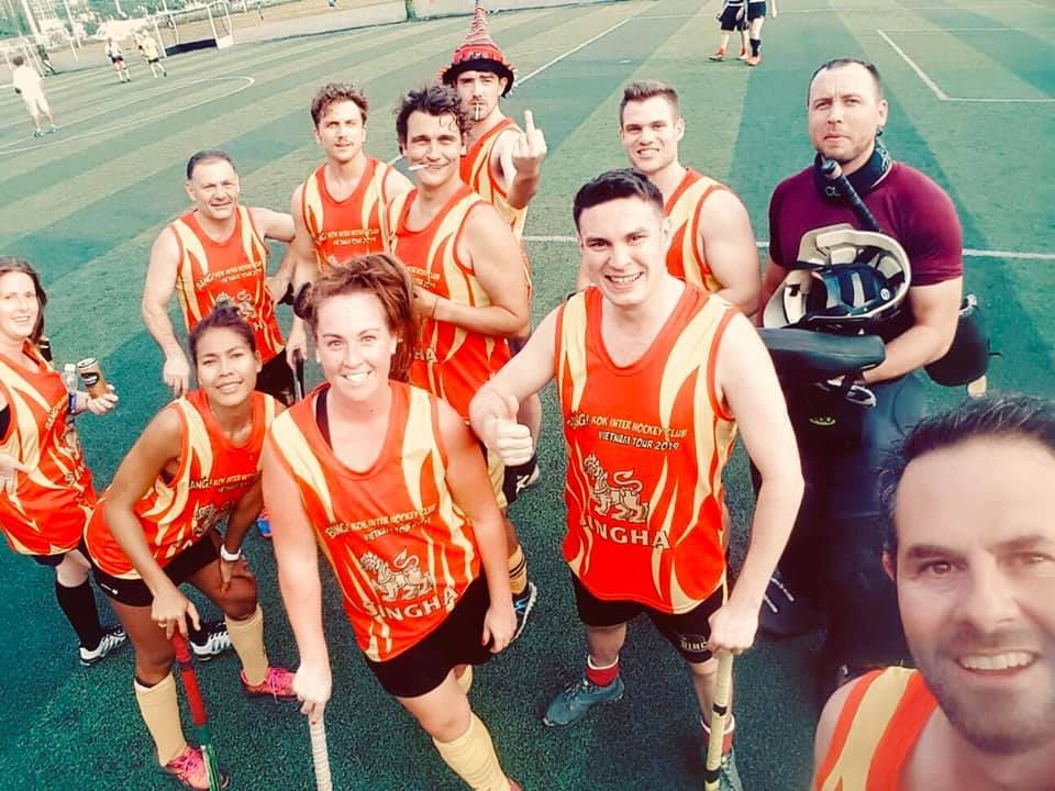 A group of people are posing for a picture and one of them is wearing a shirt that says singha