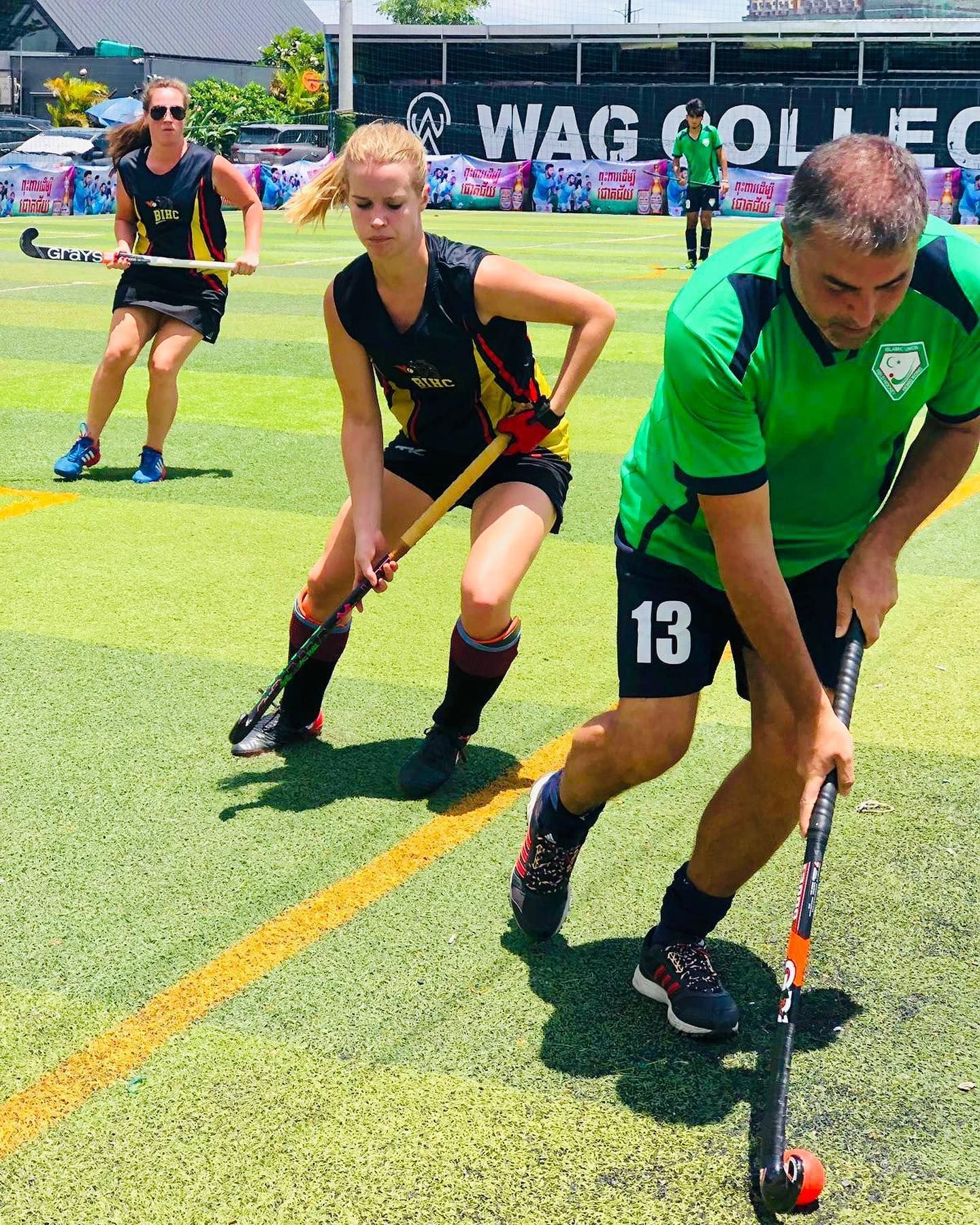A group of people are playing field hockey on a field.