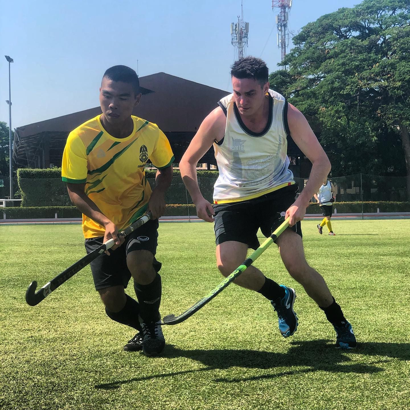 Two men are playing field hockey on a field
