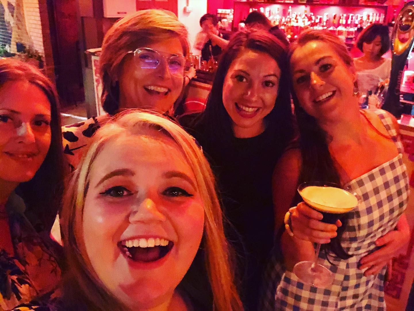 A group of women are posing for a selfie in a bar.