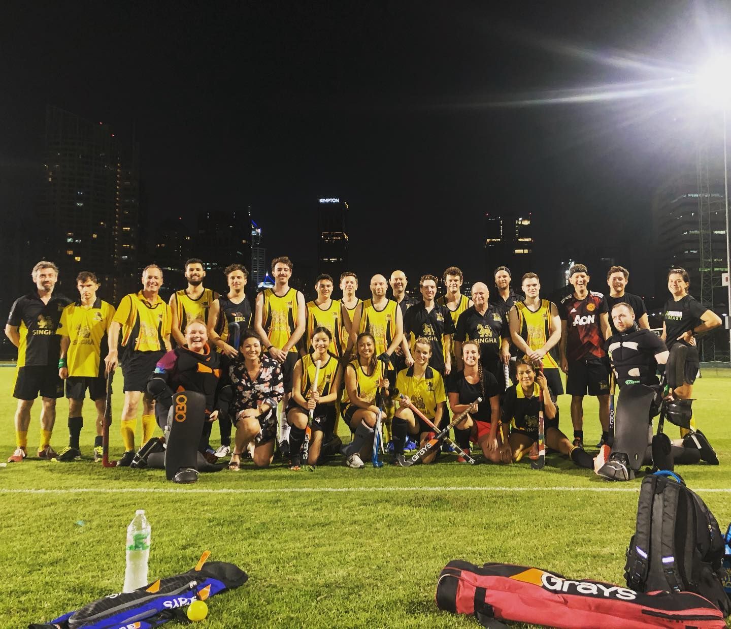 A group of people are posing for a picture on a field at night.
