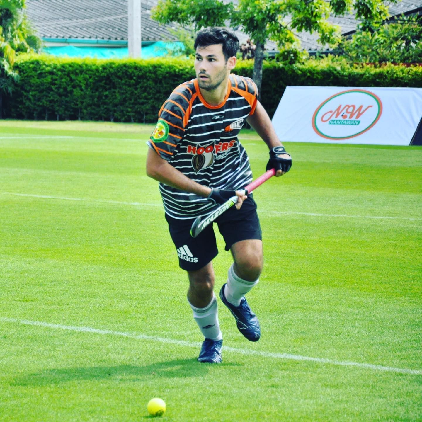 A man in a striped shirt is playing field hockey