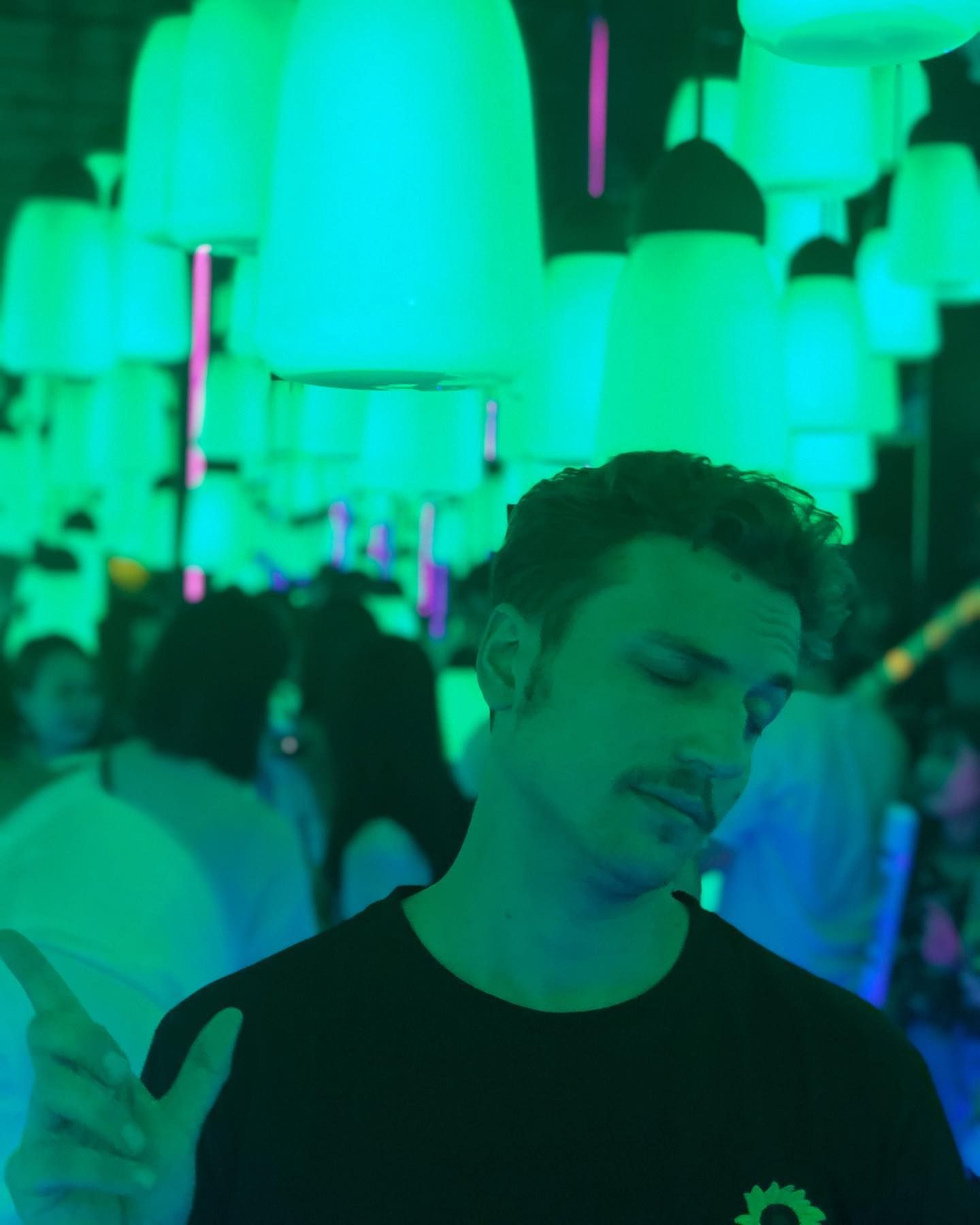 A man is standing in front of a bunch of green lights.