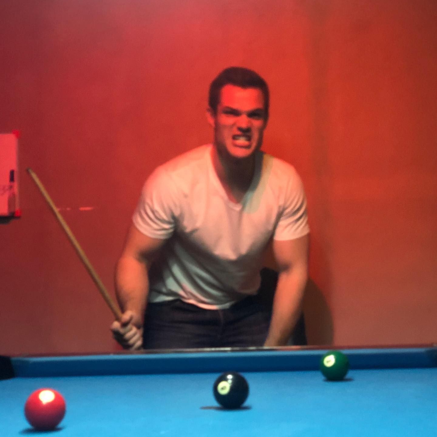 A man is holding a pool cue on a pool table