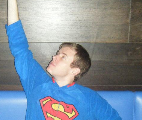 A man wearing a blue superman shirt is reaching up