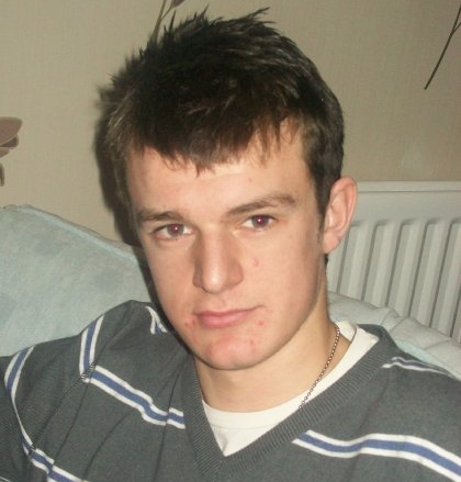 A young man wearing a grey and blue striped shirt