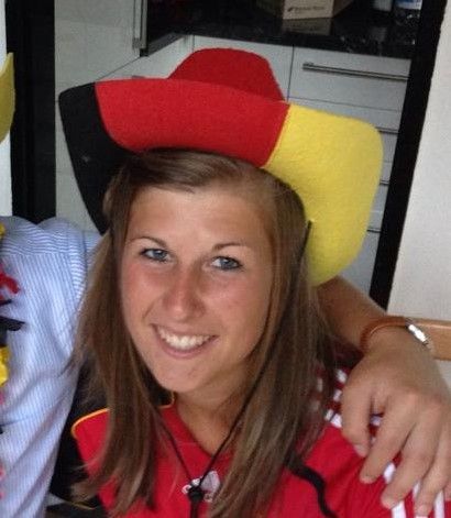 A woman wearing a red and yellow hat smiles for the camera