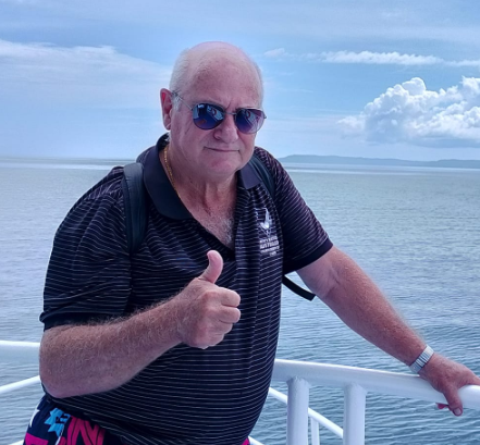 A man wearing sunglasses is giving a thumbs up on a boat