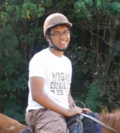 A man wearing a helmet is riding a horse