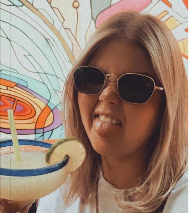 A woman wearing sunglasses is holding a margarita