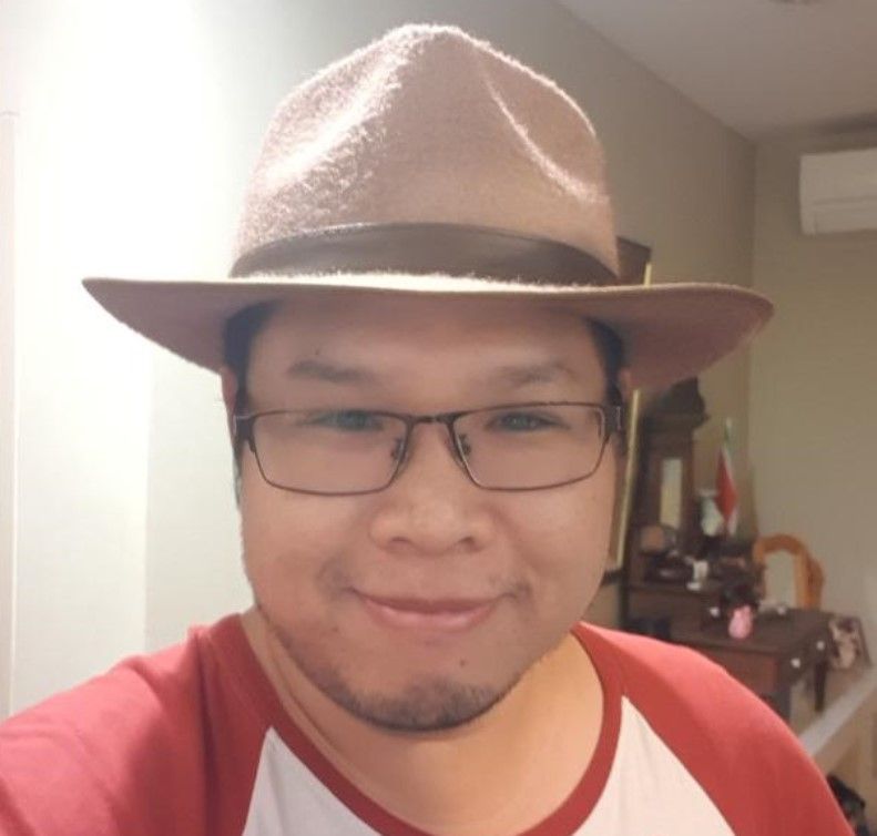A man wearing a hat and glasses is smiling for the camera