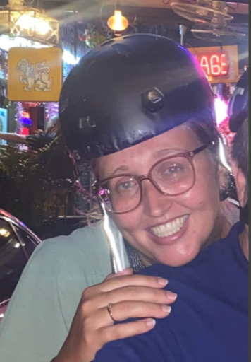 A woman wearing a helmet and glasses holds a drink