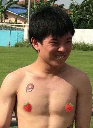 A shirtless man with strawberries on his chest and a skull tattoo on his chest.