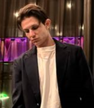 A man in a suit and white shirt is looking down