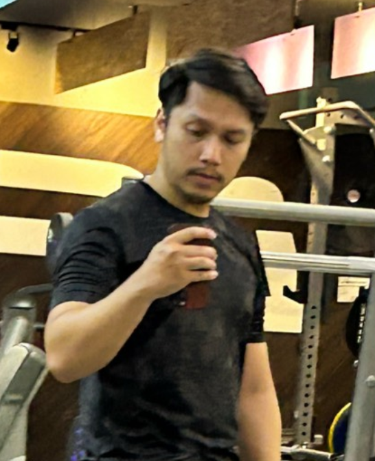 A man in a black shirt is standing in a gym