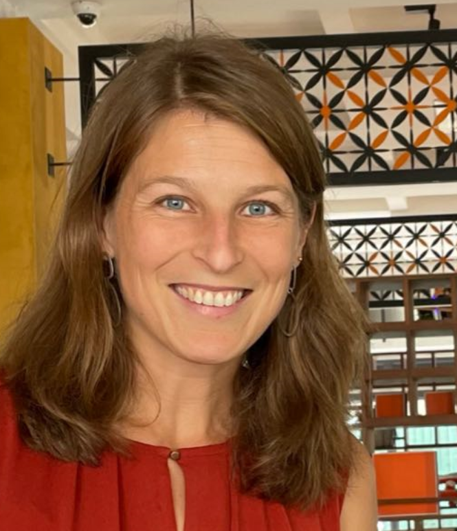 A woman in a red shirt is smiling for the camera