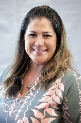 A woman in a floral shirt is smiling for the camera.