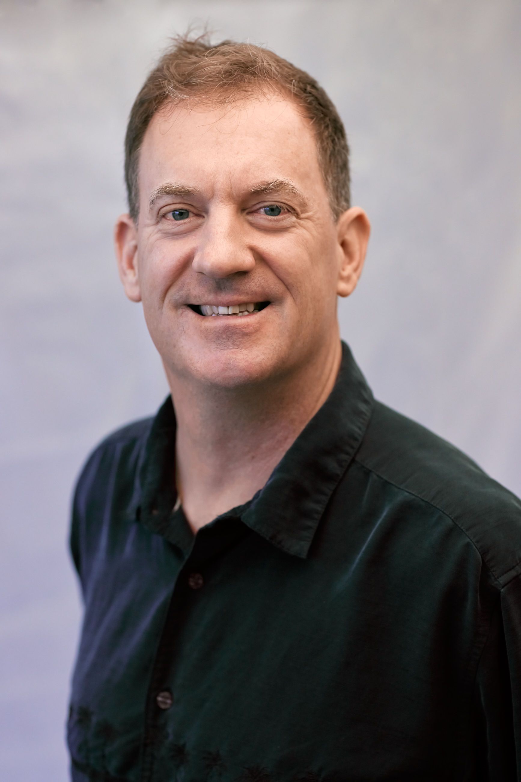 A man in a black shirt is smiling for the camera.