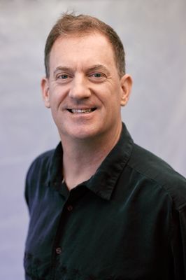 A man in a black shirt is smiling for the camera.