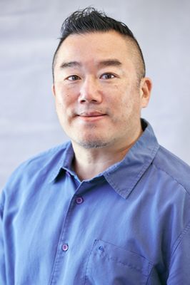 A man in a blue shirt is smiling for the camera.