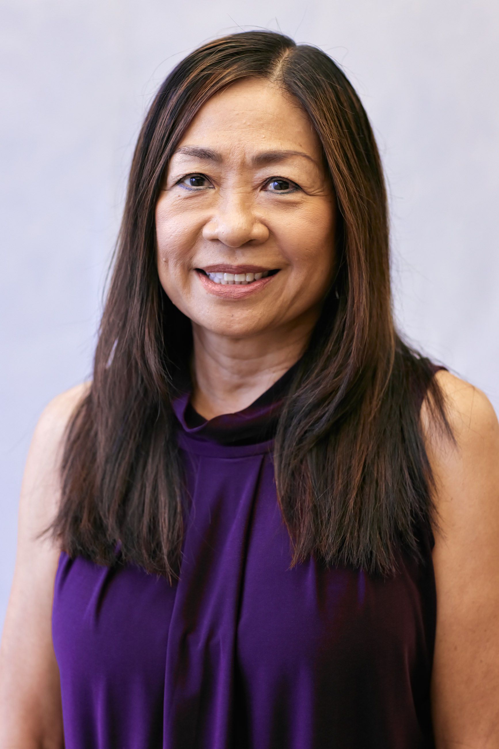 A woman in a purple shirt is smiling for the camera.