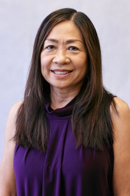 A woman in a purple shirt is smiling for the camera.
