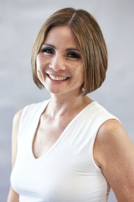 A woman in a white tank top is smiling for the camera.