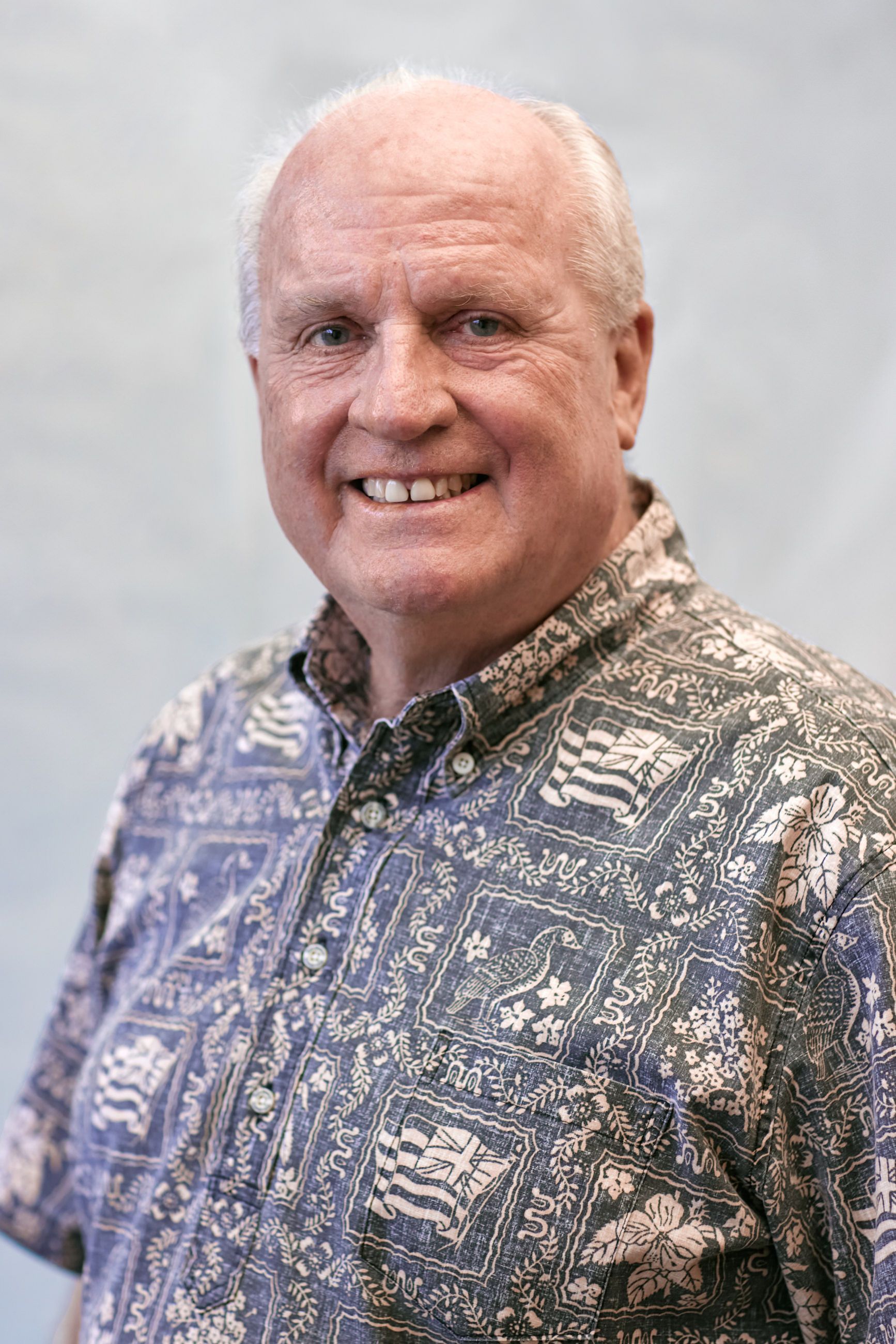 A man in a hawaiian shirt is smiling for the camera.